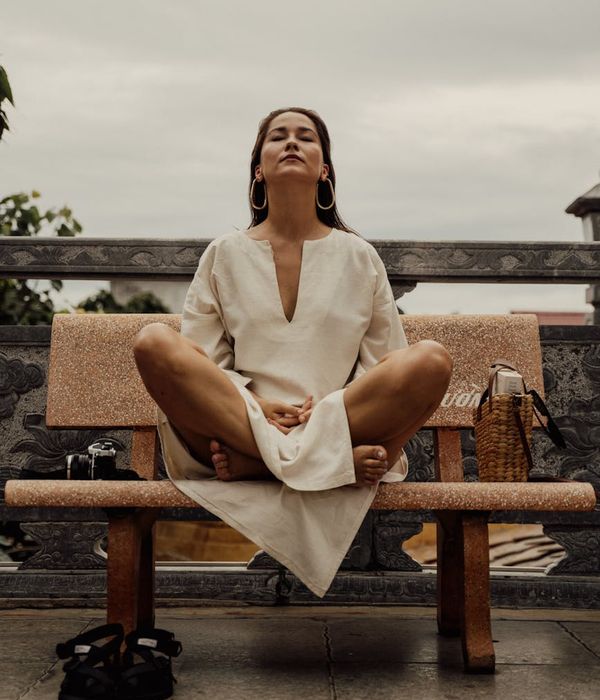 Woman in a calming yoga pose, bathed in deep purple and lime colors.